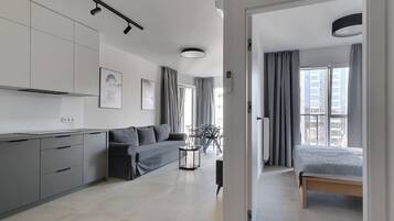 A modern, well-lit living area with a sofa, a small round table, and a bed.