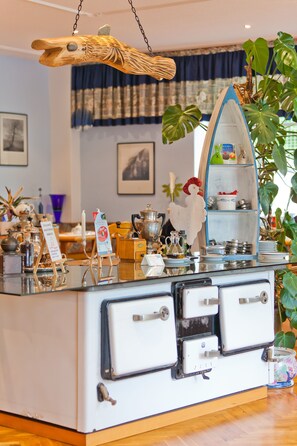 A kitchen counter with vintage appliances, a hanging fish decoration, and a shelf with kitchenware. - Hotel Villa Subklew (Sellin)