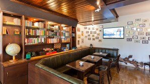 Una biblioteca con estanterías, un globo terráqueo y un televisor en la pared.