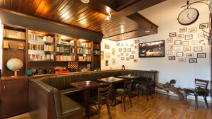 Una biblioteca acogedora con estanterías, un reloj y cuadros en la pared.