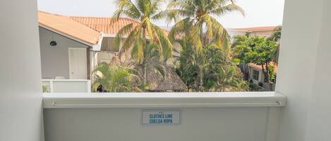 A white plastic chair on a balcony with a sign reading "CLOTHES LINE CUEGLA ROPA".