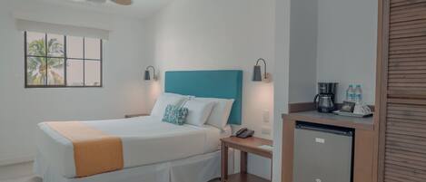 A hotel room with a bed, a desk, a coffee maker, and a mini fridge.