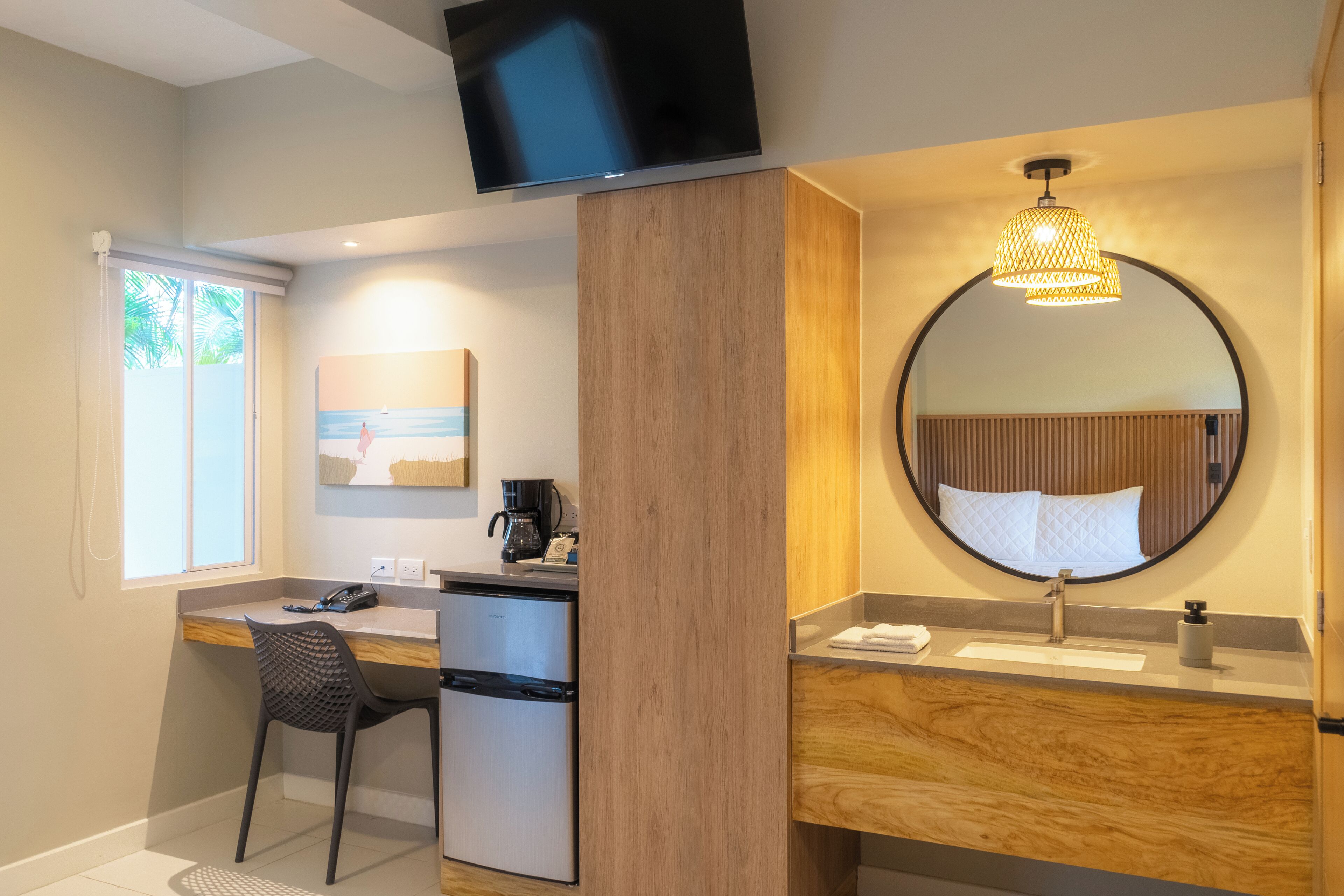 A modern bathroom with a round mirror, a sink, a toilet, and a small desk with a chair.