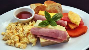 Een bord met roerei, ham, kaas, toast en een klein schaaltje jam.