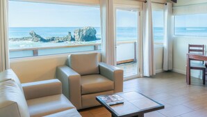 A room with a view of the ocean, a sofa, a table, and a chair. - Hotel Roca Sunzal (Tamanique)