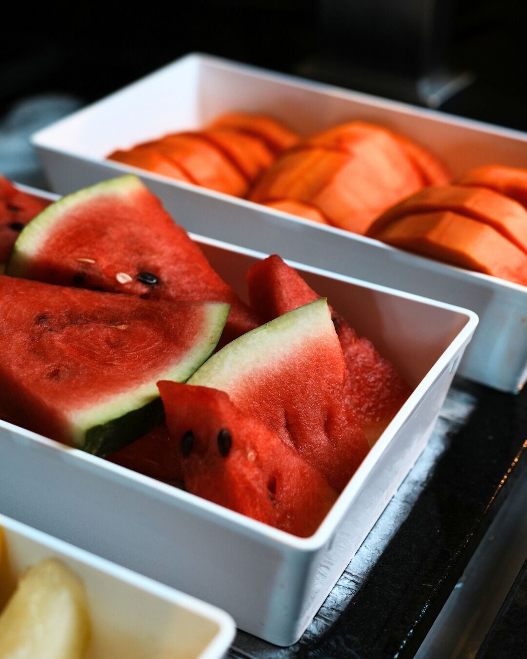 A buffet with watermelon and cantaloupe slices.