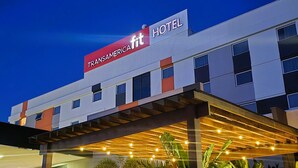 A hotel with a modern design, featuring a covered outdoor seating area with chairs and potted plants. - Transamerica Fit Catalão (Catalao)