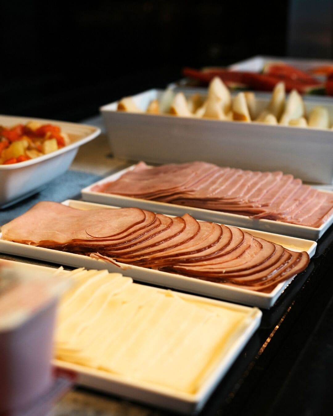 A buffet with various food items including sliced meats and cheeses.