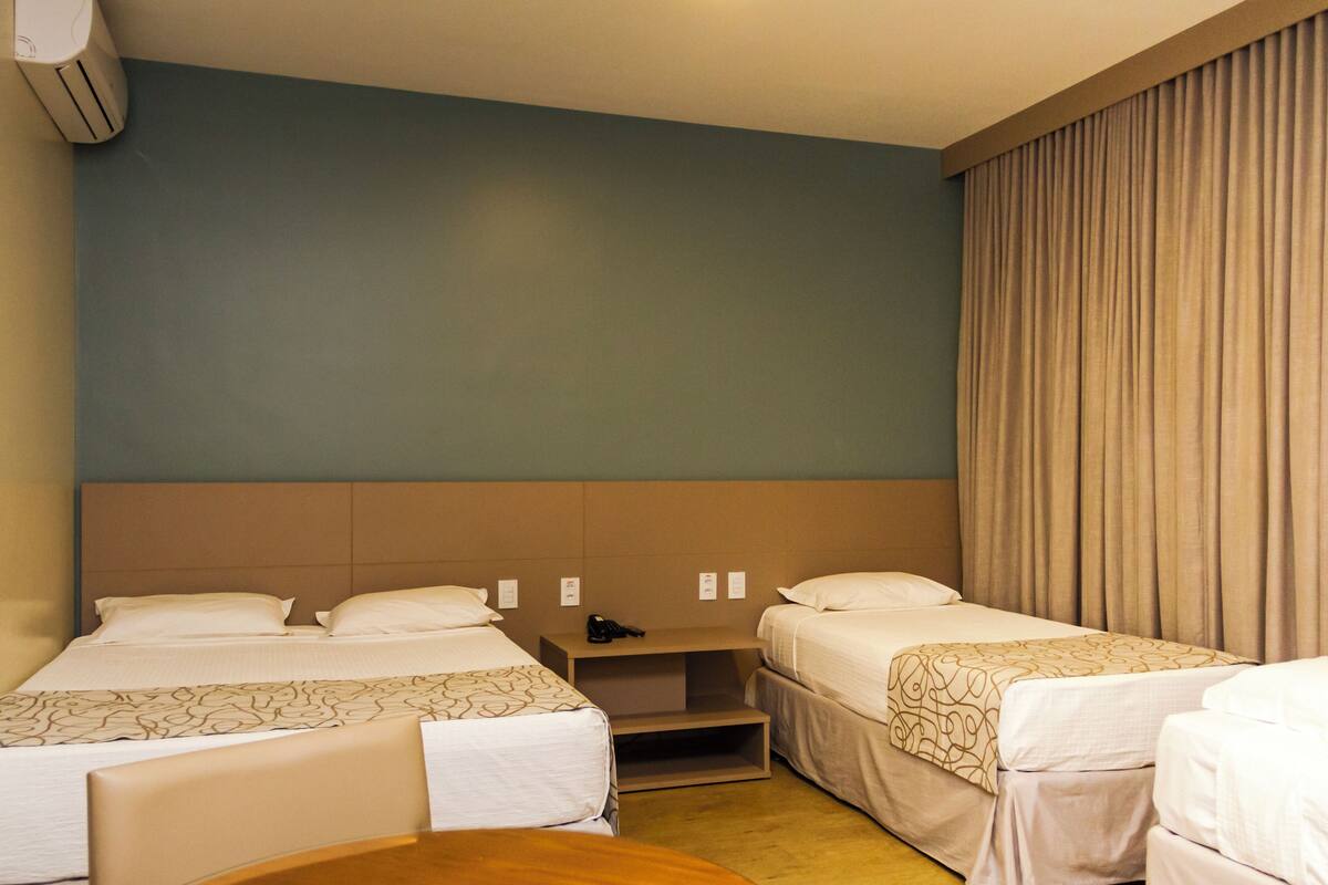 A hotel room with two single beds, a nightstand, and a small table.