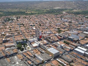 A hotel with a prominent red and white sign, surrounded by a dense urban area with various buildings and streets. - Panorama Hotel (Juazeiro do Norte)