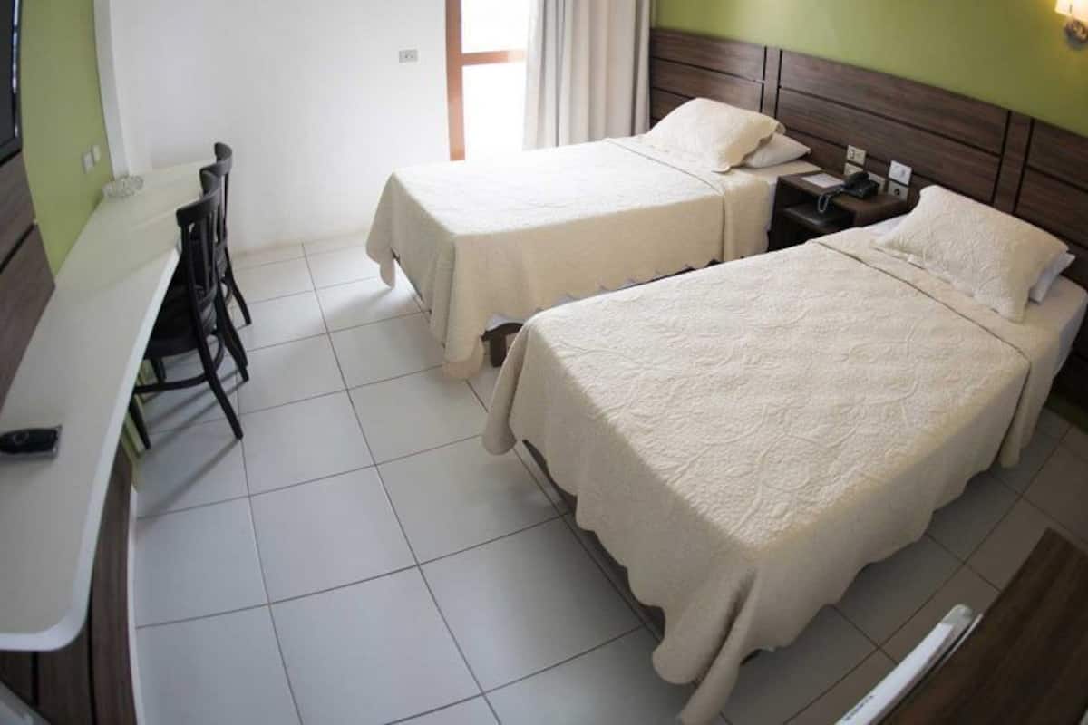 Habitación de hotel con dos camas, un escritorio y un televisor.