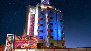 Un hôtel à plusieurs étages, doté d’une enseigne lumineuse et d’une grande affiche sur la façade indiquant « Prolongez votre séjour ».