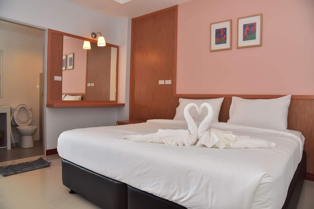 Una camera d'albergo con un letto grande, una testiera in legno, uno specchio e due quadri appesi al muro.