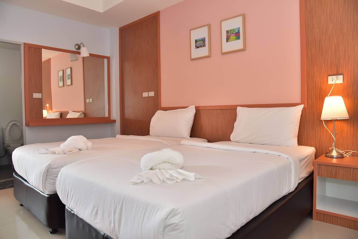 Camera d'albergo con due letti, un grande specchio, un comodino con una lampada e due quadri appesi al muro.