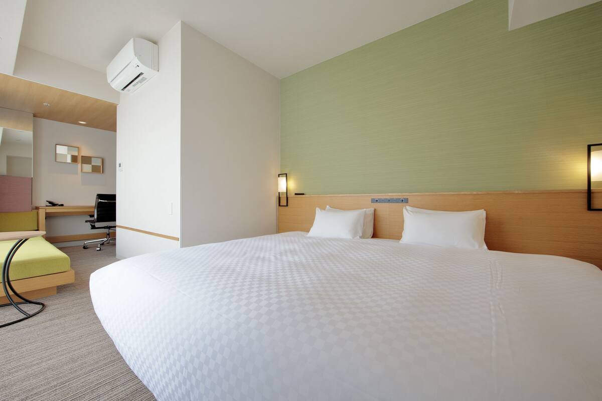 Una habitación de hotel con una cama grande, un escritorio con silla y un pequeño rincón de descanso.