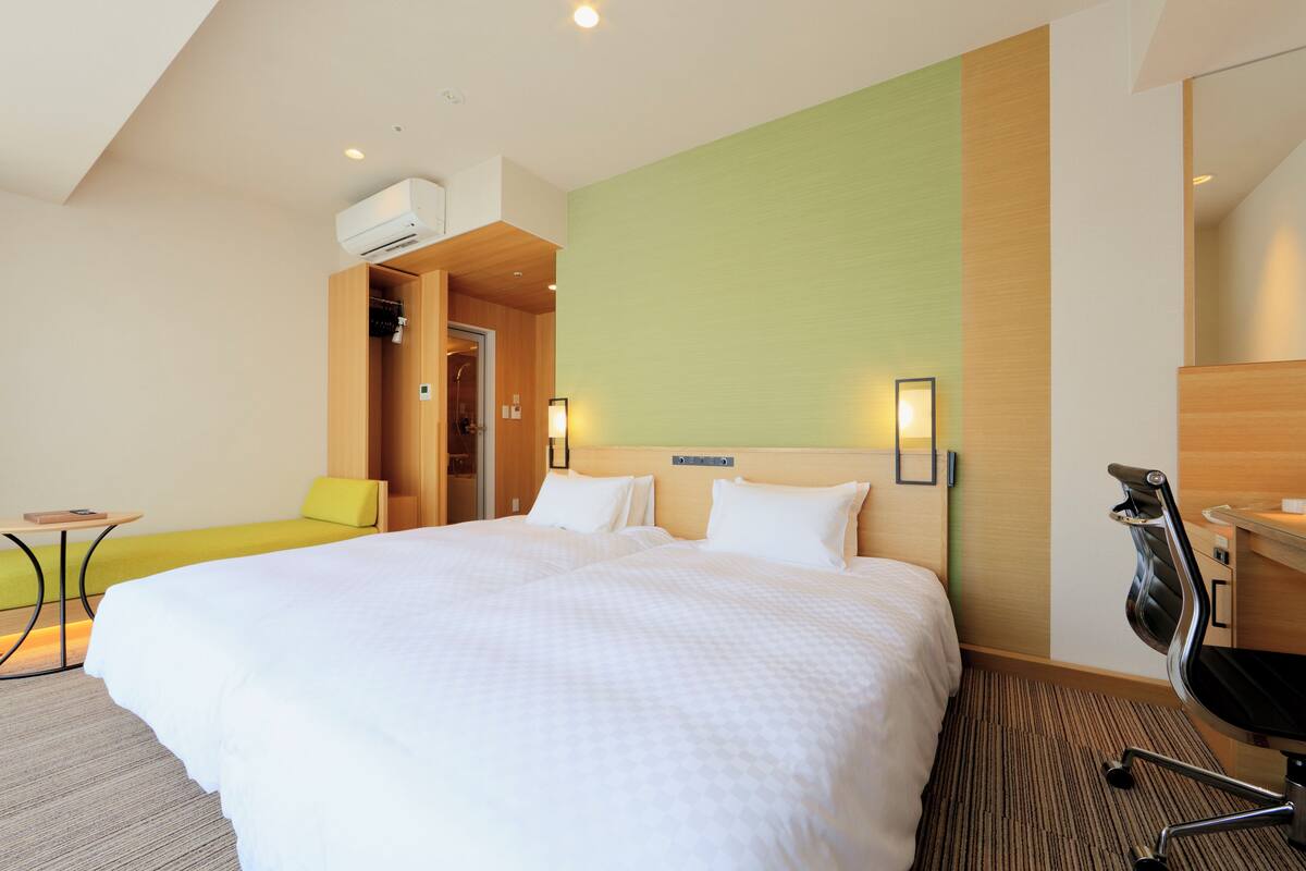 Una habitación de hotel con una cama grande, un escritorio, una silla y una mesita.