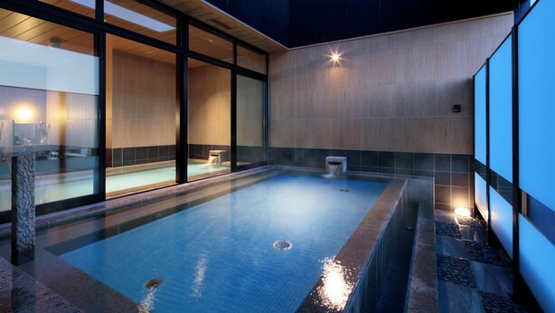 Una piscina interior moderna con paredes de vidrio transparente, interior de madera y un accesorio de iluminación en forma de estrella.