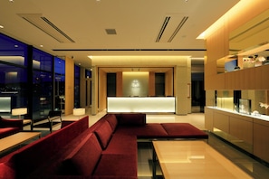 Un hall d’hôtel moderne comprenant un comptoir d’accueil, un espace salon et une présentation d’objets décoratifs.