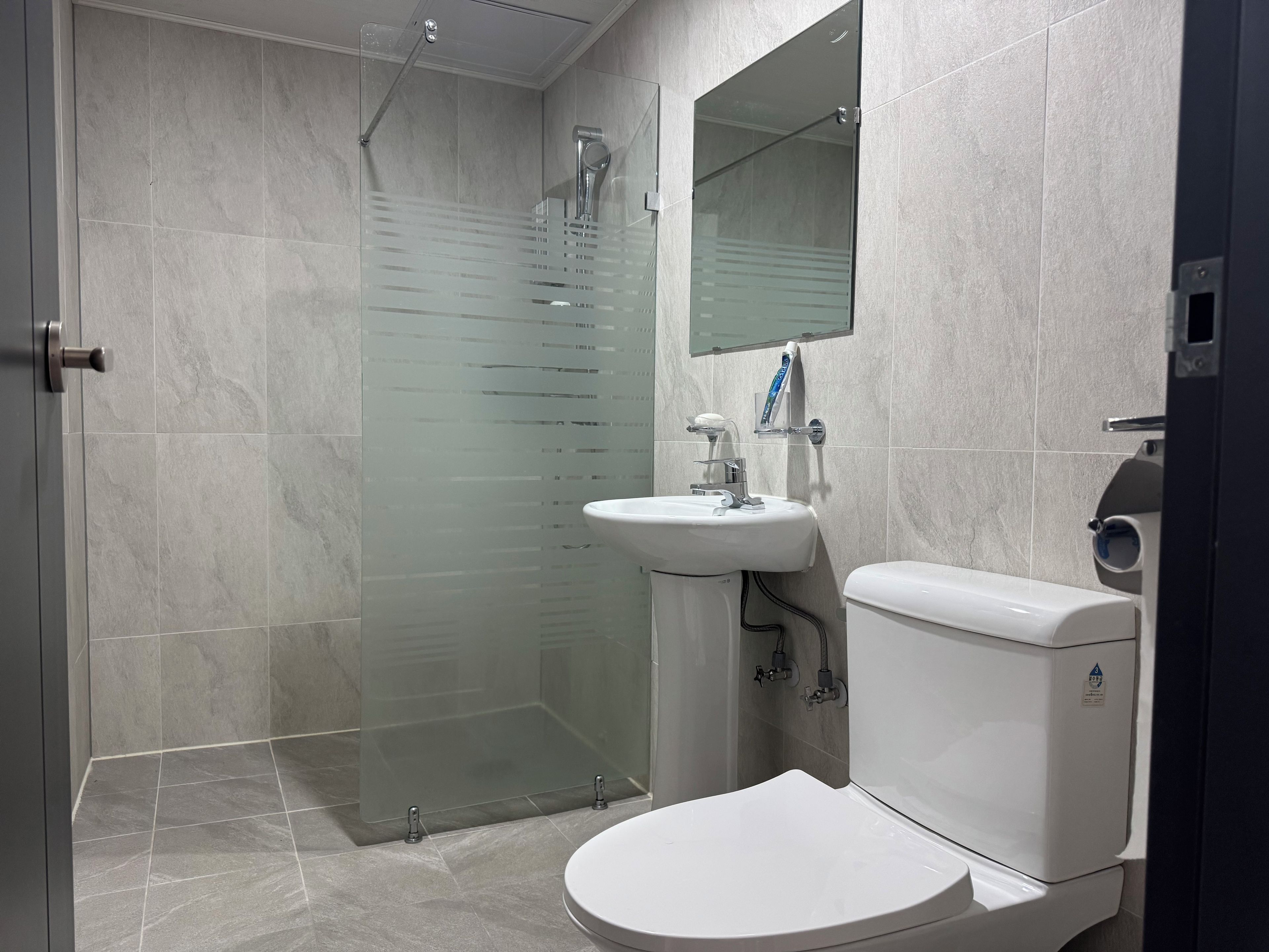 Un baño con cabina de ducha de vidrio, un lavamanos blanco y un inodoro.