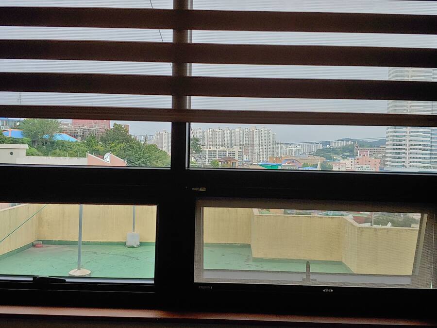 A window with multiple panes, each offering a view of a residential area with buildings and greenery.