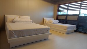 Une chambre d’hôtel moderne avec deux lits, une grande fenêtre avec stores et une vue sur la ville.