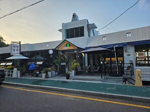 A cafe with outdoor seating, a guest house sign, and a QR code on the facade. - Mokpo White Windmill Guesthouse (Mokpo)