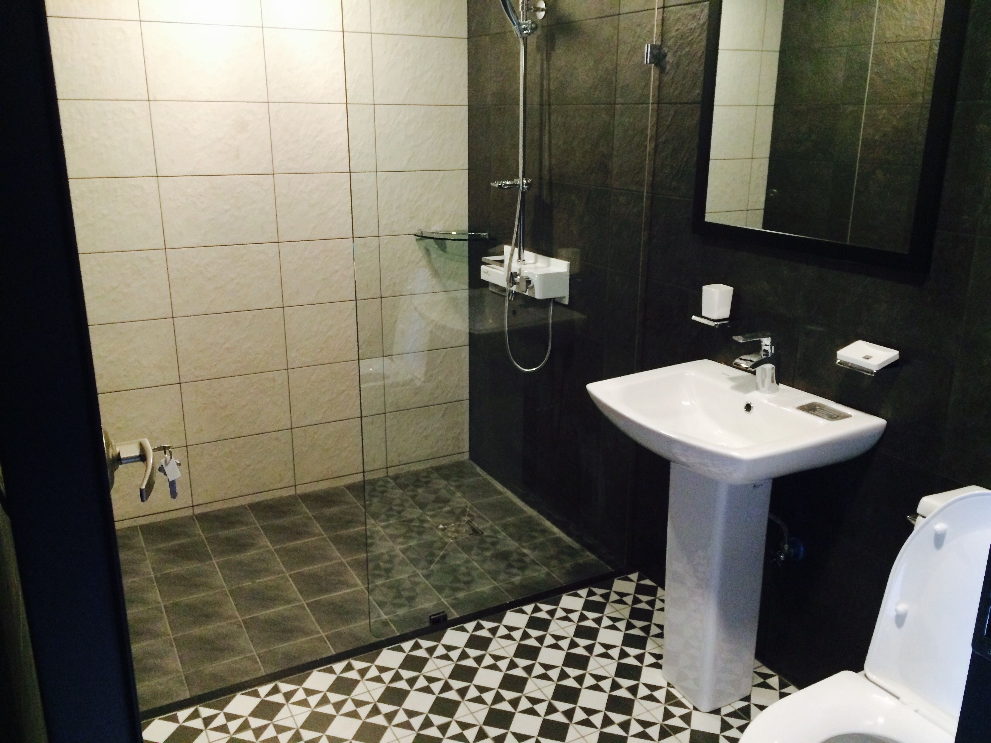 Un bany amb sòl de rajola, un lavabo, una vàter i una dutxera.
