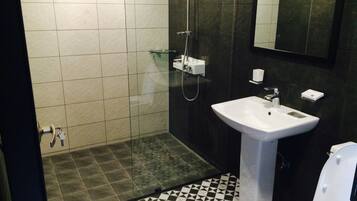 Un bany amb sòl de rajola, un lavabo, una vàter i una dutxera.