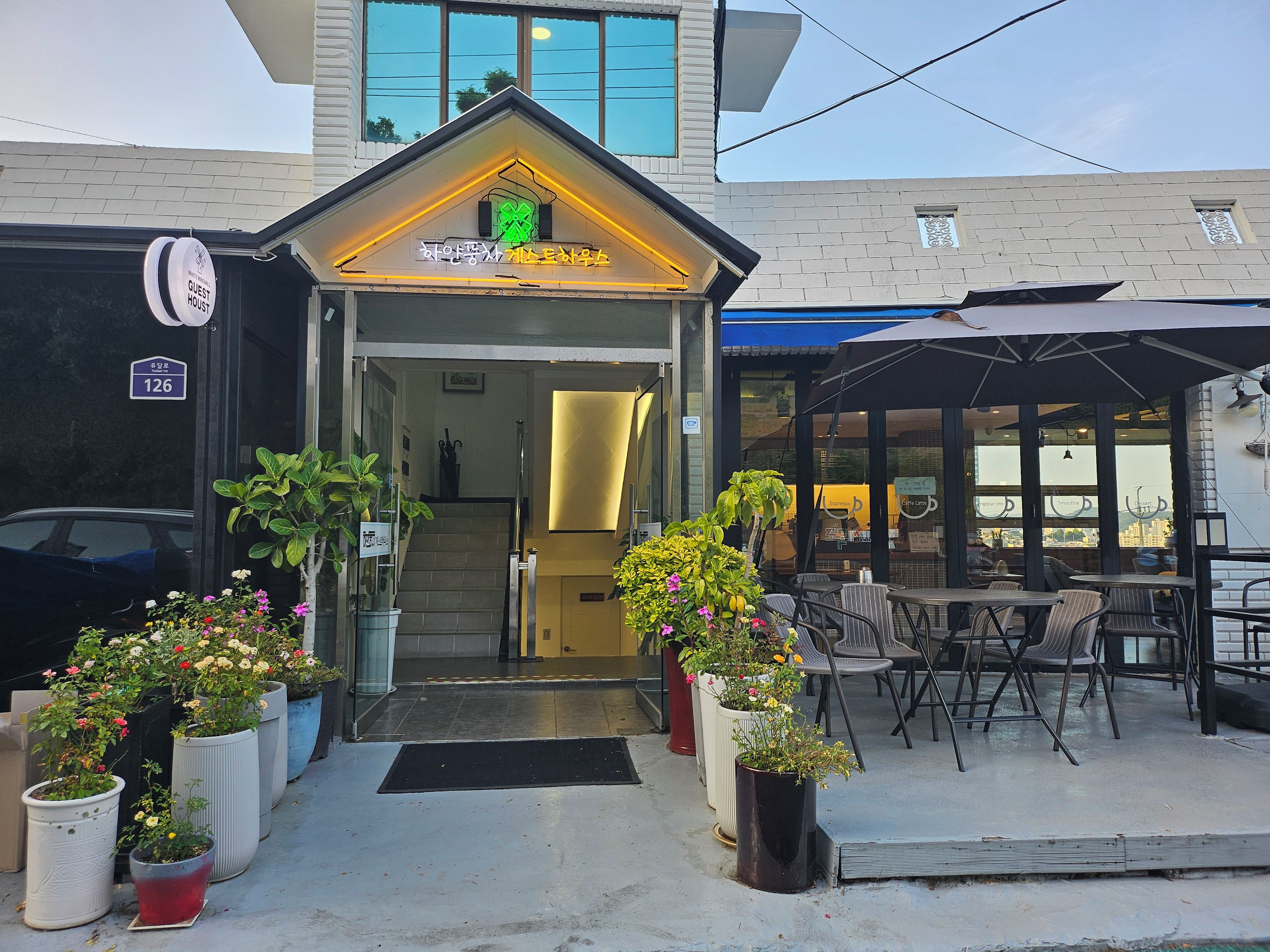 A hotel entrance with a staircase leading inside, outdoor seating area, and potted plants.