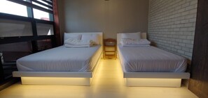 A room with two beds, each with a headboard and a bedside table. The beds have white bedding and are illuminated by under-bed lighting. - Mokpo White Windmill Guesthouse (Mokpo)