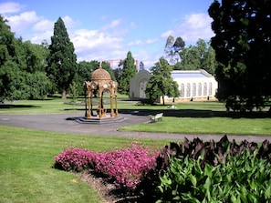 Ein Pavillon in einem Park mit einem Gebäude im Hintergrund.