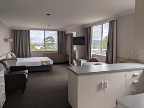 A hotel room with a bed, a desk, a chair, and a view of the outdoors. - Parklane Motel (Launceston)