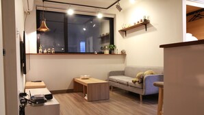A modern living room with a sofa, a coffee table, a TV, and a window with a view. - Hongdae Sopoong the Urban (Seoul)
