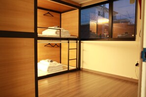A room with a wooden floor and a window. There are two beds with white linens and a coat rack. - Hongdae Sopoong the Urban (Seoul)