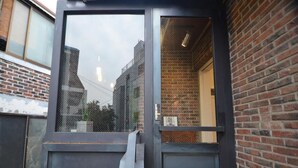 A door with a window, a brick wall, and a metal fence. - Hongdae Sopoong the Urban (Seoul)