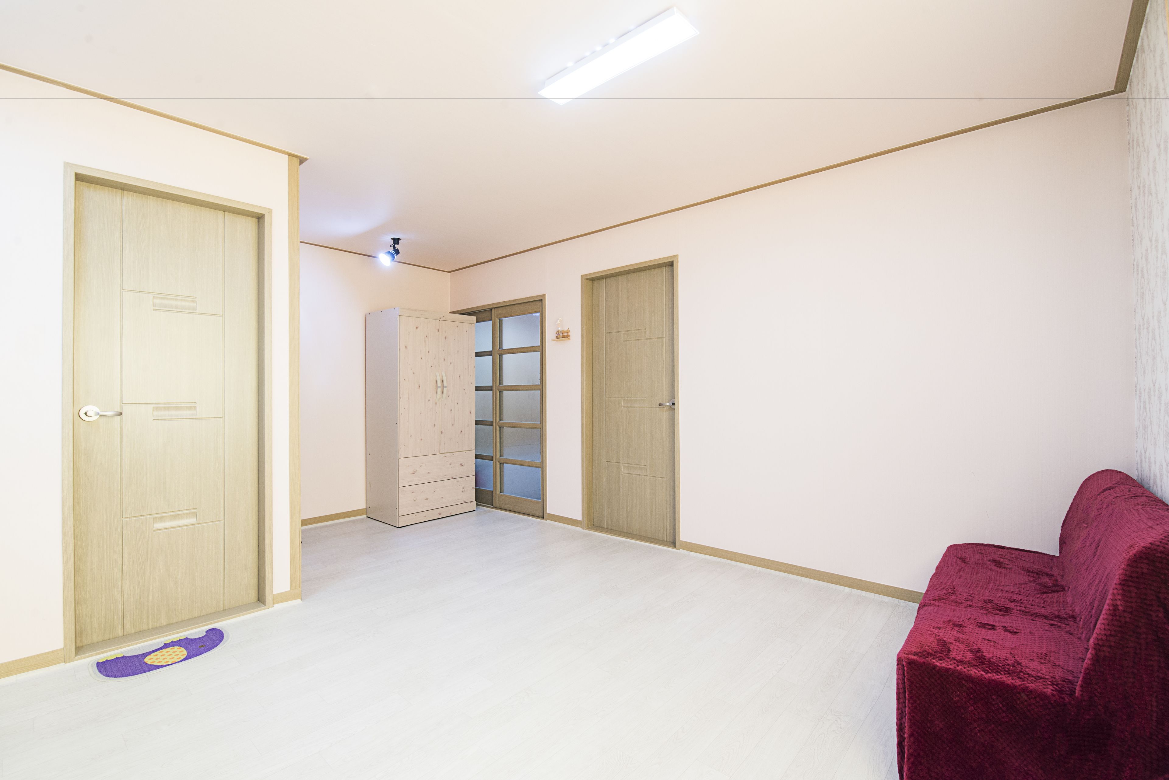 A room with two doors, a red chair, and a purple mat on the floor.