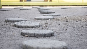 Un sentier bordé de pierres circulaires servant de marchepieds, qui mène à l’entrée d’un bâtiment.