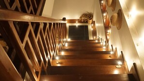 A wooden staircase with a geometric railing design, leading to a higher floor. - WEStay @ Chillax House - Ngapali - Hostel (Ngapali)