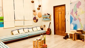A cozy room with a striped sofa, a wooden door, a guitar, and a map on the wall. - WEStay @ Chillax House - Ngapali - Hostel (Ngapali)