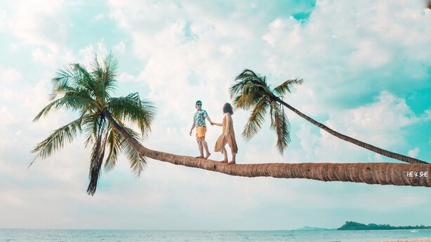 A couple walking on a palm tree branch over a beach with the sea and a distant island in the background. - WEStay @ Chillax House - Ngapali - Hostel (Ngapali)