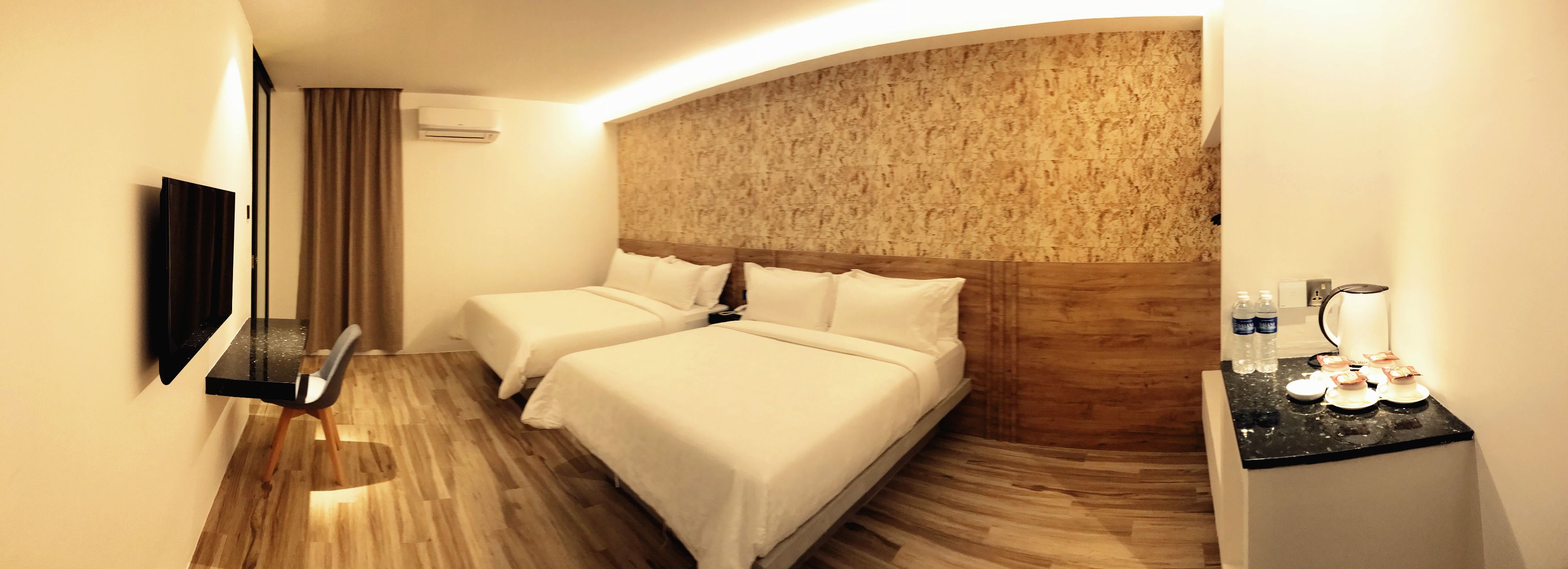 A hotel room with two beds, a flat-screen TV, a minibar, and a wooden headboard.