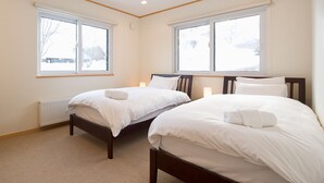 Quarto com duas camas de solteiro, um radiador e duas janelas.