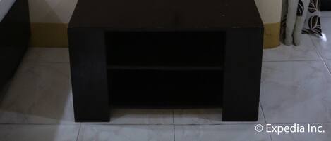 Un téléviseur fixé au mur, une télécommande posée sur une petite table et une prise de courant.