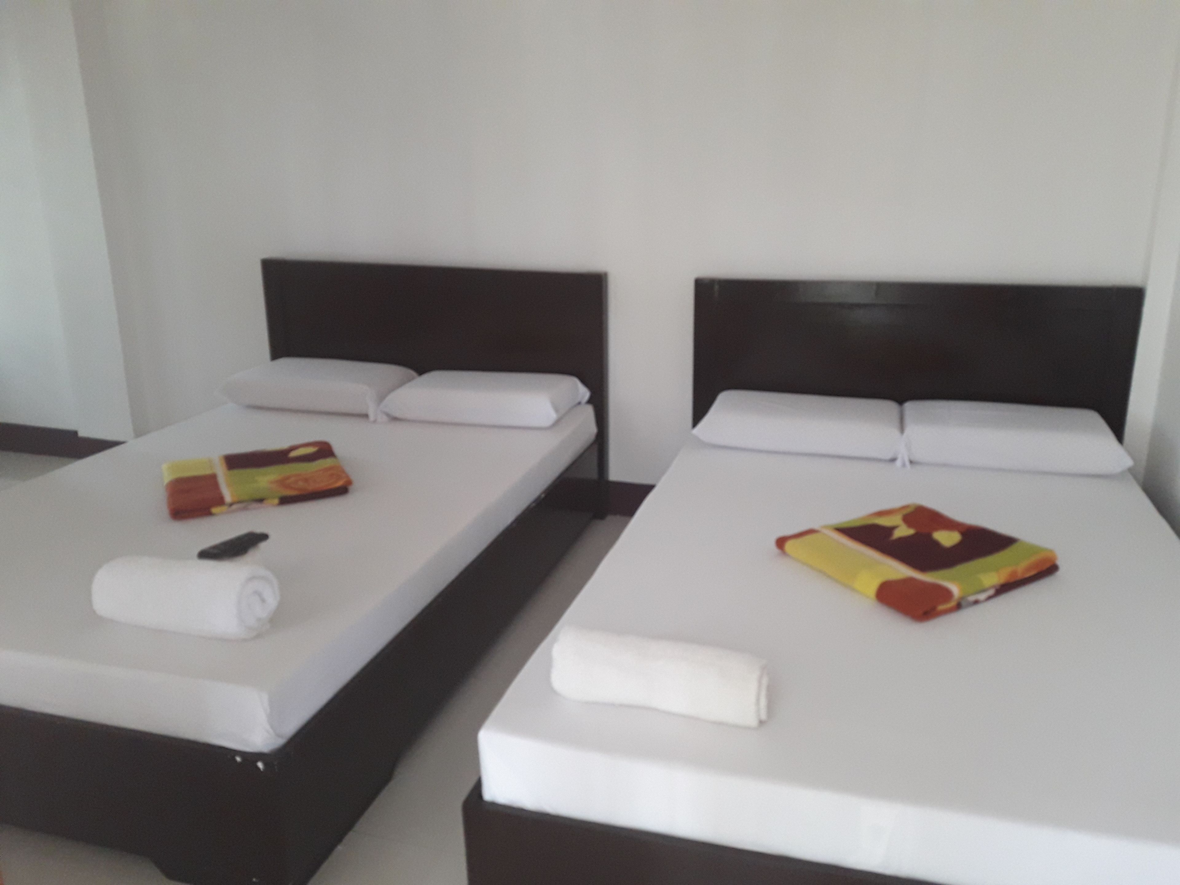 Two single beds with white linens, black headboards, and colorful blankets.