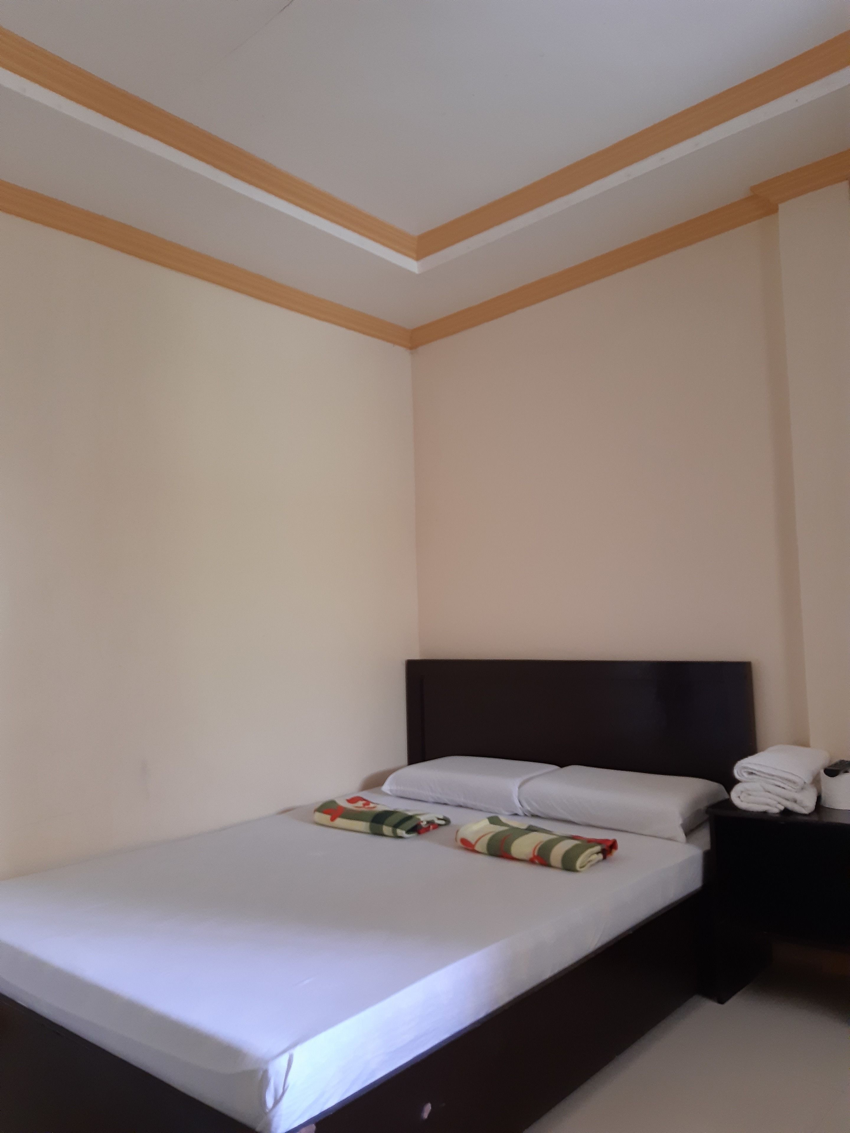 A hotel room with a single bed, a dark headboard, and a nightstand with towels.