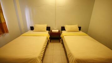 A small, clean room with two single beds, a nightstand, and a wall-mounted light.