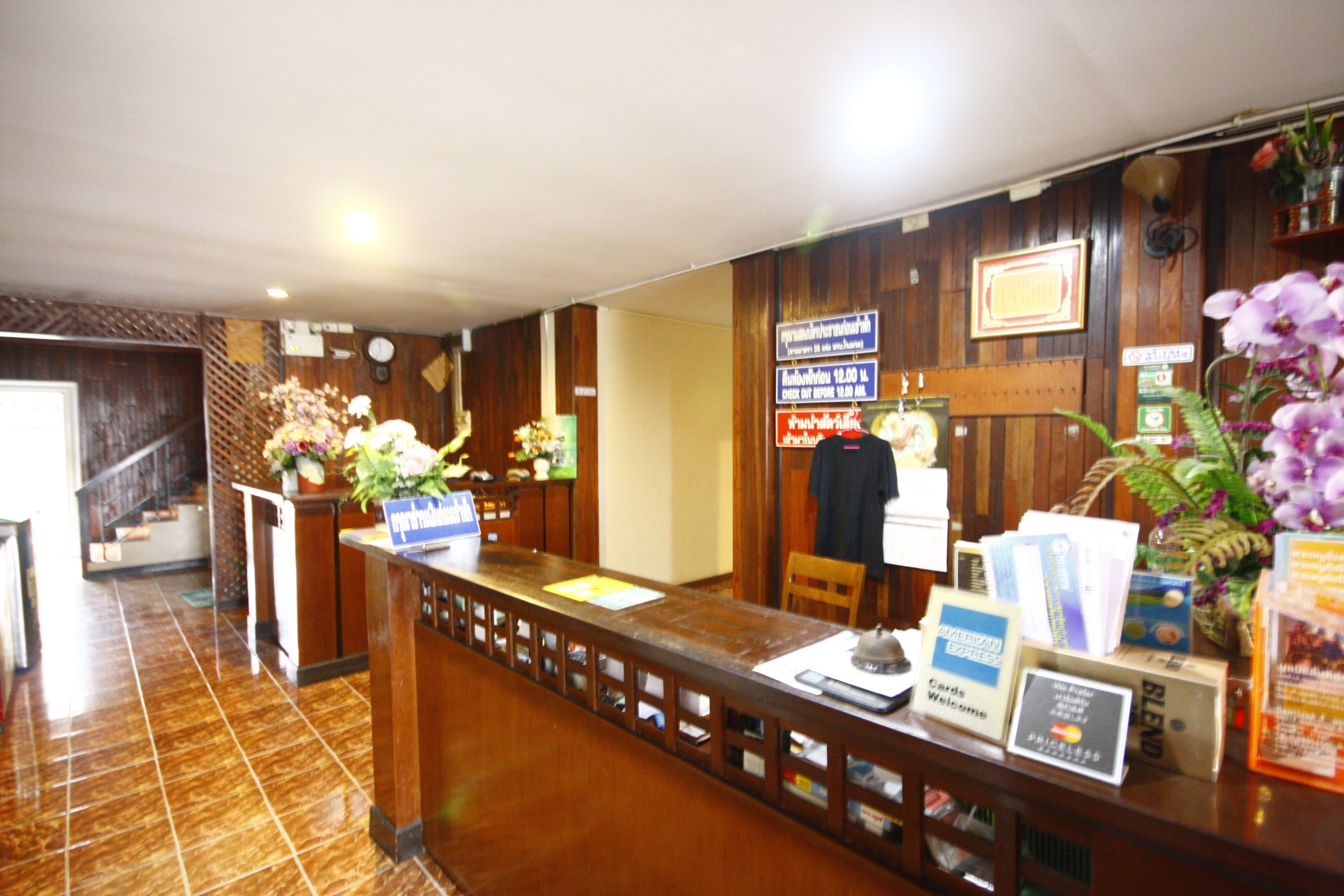 Una recepción con un mostrador de madera, un reloj y un cartel con el nombre del hotel.