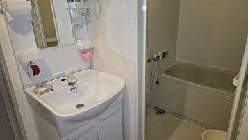 Un baño con lavamanos blanco, espejo, inodoro y bañera.