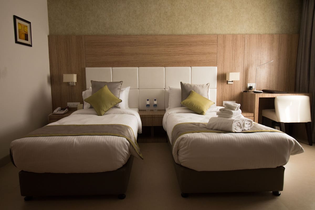 A hotel room with two beds, a desk, and a chair.