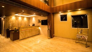A hotel lobby with a reception desk, a large vase with flowers, and a bulletin board. - The Maureen (Barasat)